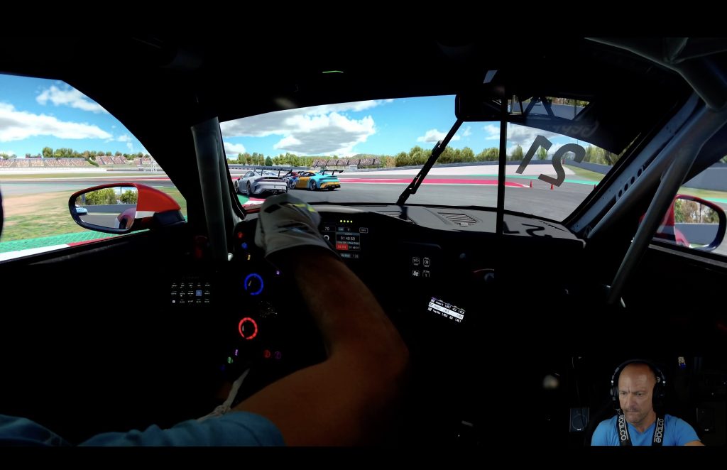 Cockpit view from the Porsche Cup Barcelona race, gloved hands on the wheel chasing GT cars into a corner on lap 9.