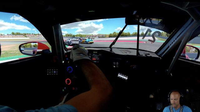 Cockpit view from the Porsche Cup Barcelona race, gloved hands on the wheel chasing GT cars into a corner on lap 9.